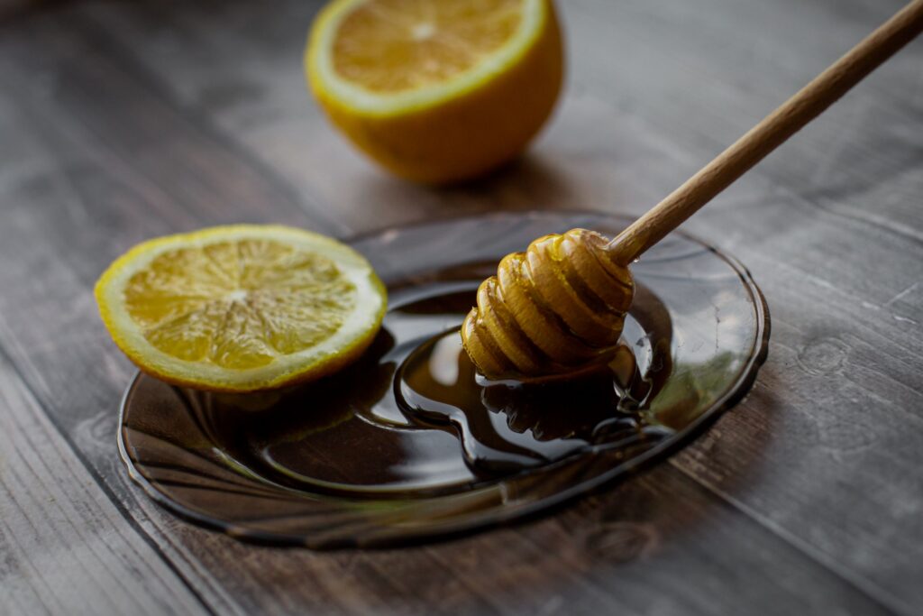 Miel y rodajas de limón sobre una mesa, ingredientes comúnmente utilizados para aliviar la irritación de garganta asociada con la tos con flemas.