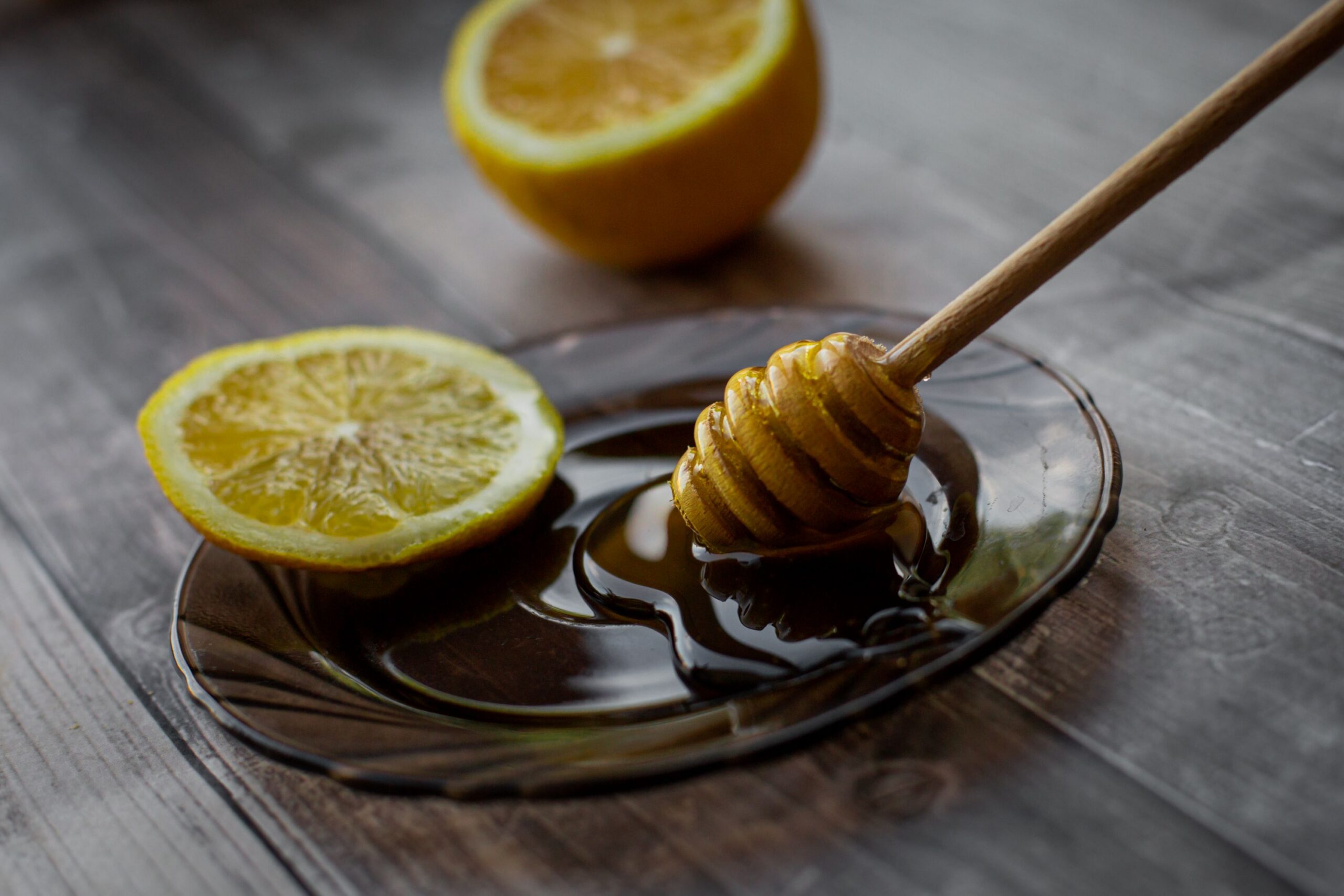 Miel y rodajas de limón sobre una mesa, ingredientes comúnmente utilizados para aliviar la irritación de garganta asociada con la tos con flemas.