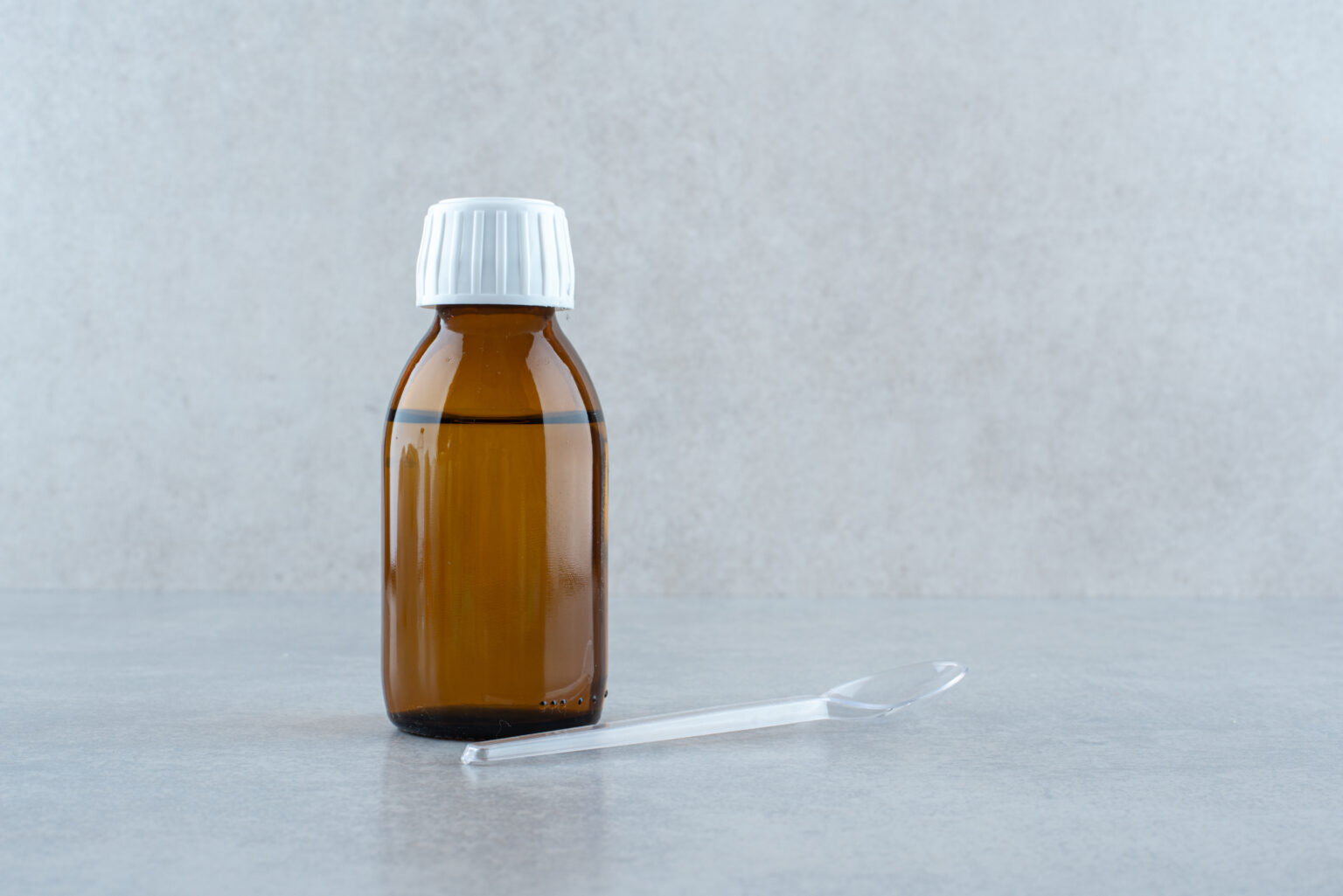 Frasco de Bronquisol para la tos acompañado de una cuchara dosificadora para administrar el tratamiento adecuado.