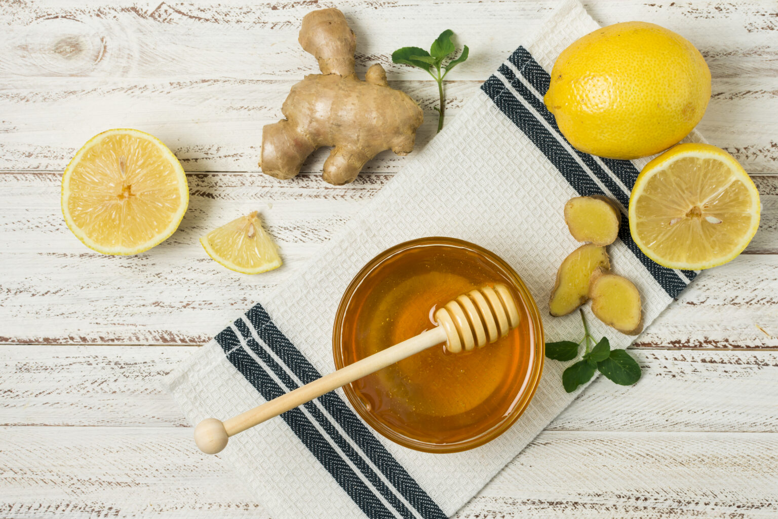 Miel, limón y jengibre dispuestos sobre una mesa como ingredientes utilizados para aliviar la tos con expectoración.