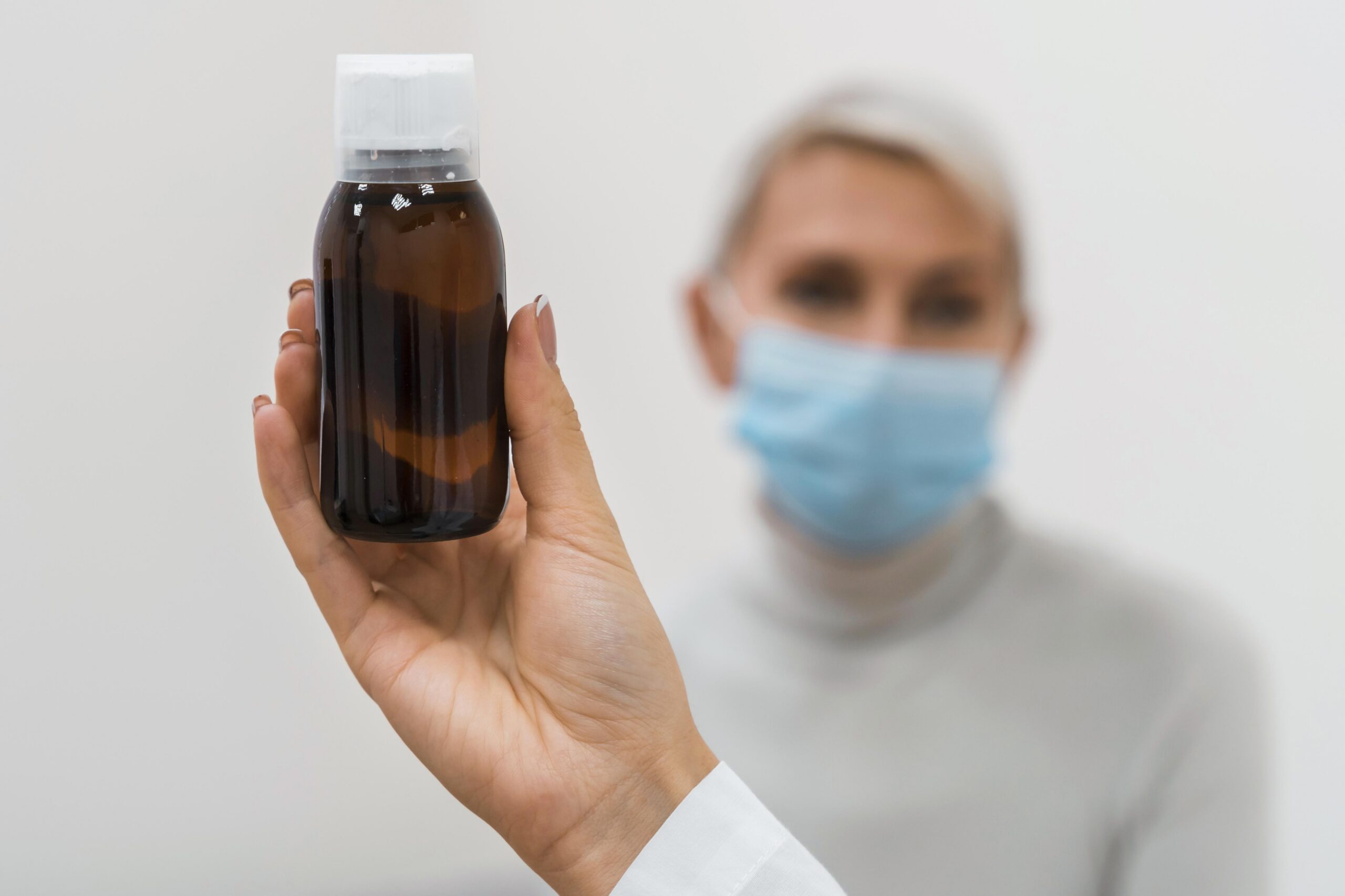 Doctora sosteniendo un Antitusivo frente a un paciente.