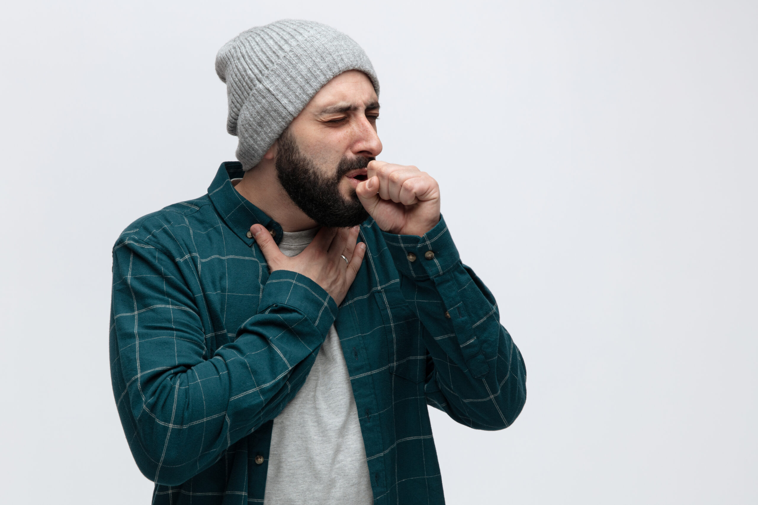 Hombre tocándose la garganta mientras tose, representando la irritación característica de la tos seca sin flema.