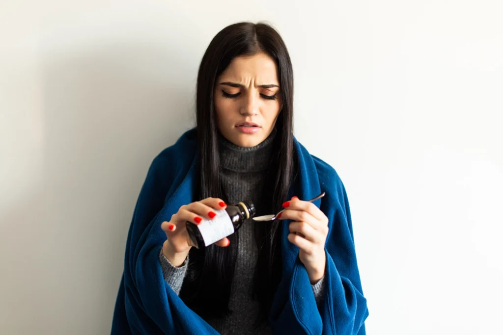Mujer adulta sosteniendo un frasco de jarabe para la tos seca.